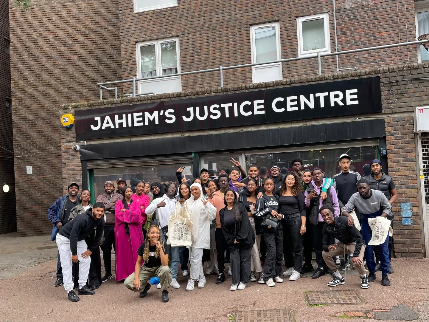 Large group of young people standing in front of Jahiem's Justice Centre, looking at the camera with a smile.