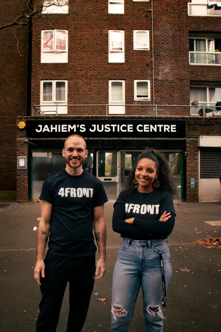 Two young people are standing in front of Jahiem's Justice Centre, looking at the camera with a smile.
